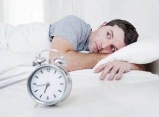 Man in bed with alarm clock