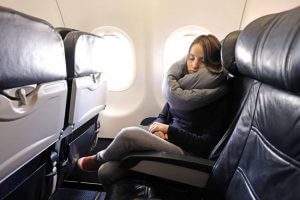 woman rests with infinity pillow on an airplane