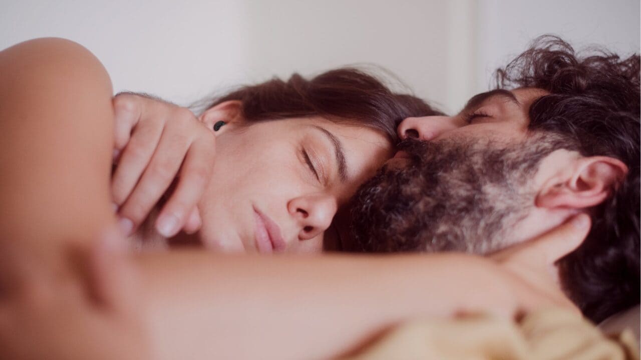 Couple asleep in bed, one wearing QuietOn 4 earbuds to block a partner's snoring