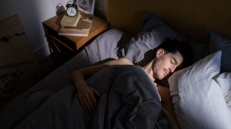 Man asleep on his side in a dim bedroom, one of the natural remedies for snoring