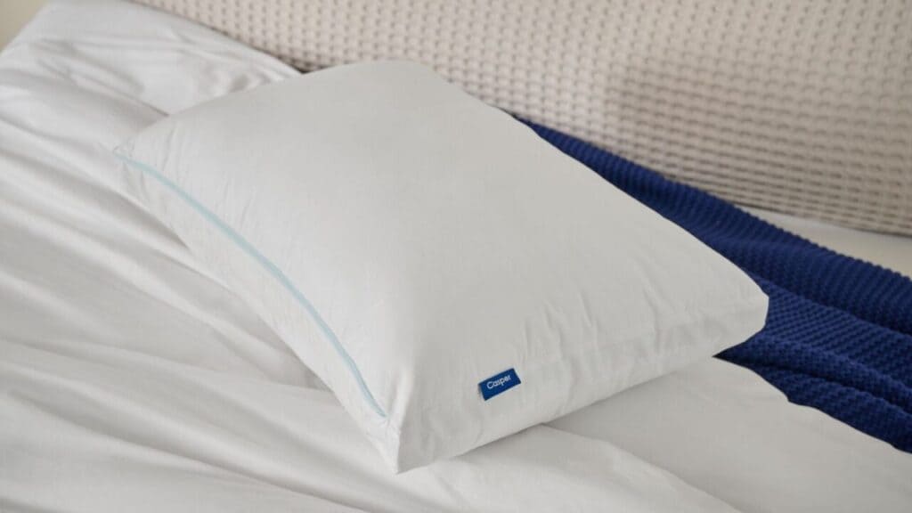 Casper Original Cooling Pillow resting on a white bed with navy throw