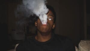 Man exhaling a cloud of vapor in a dark room