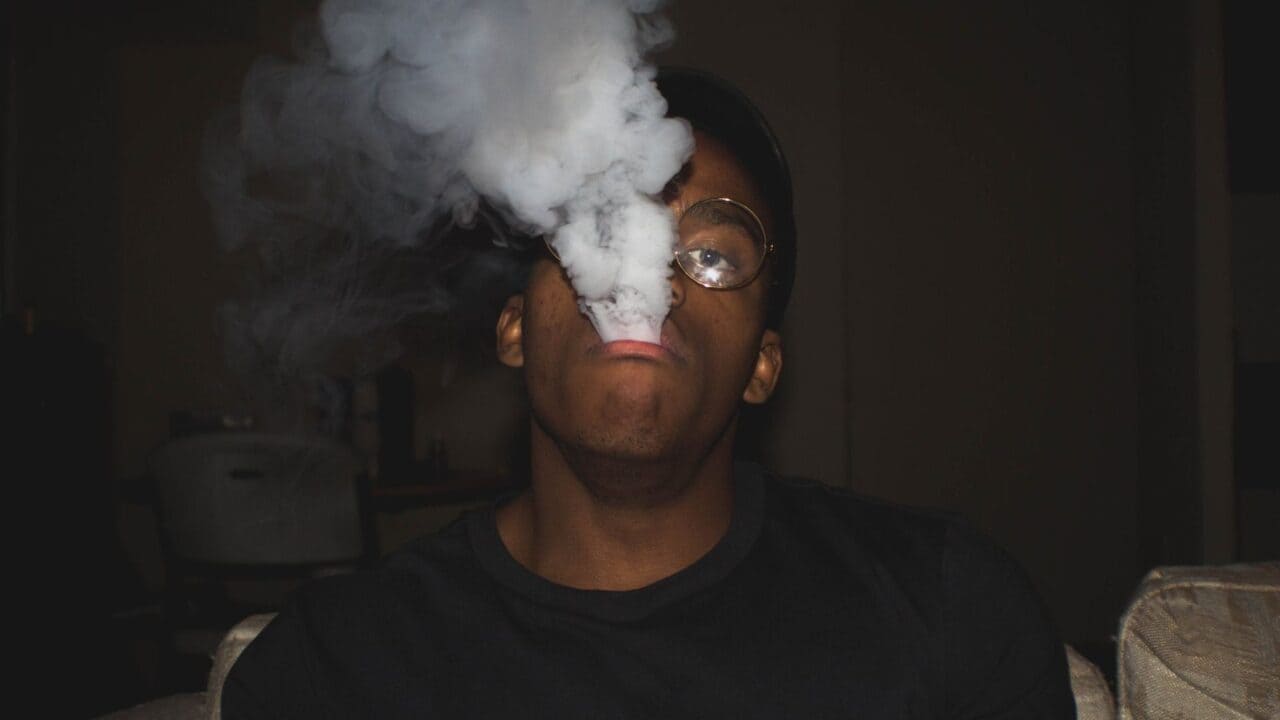 Man exhaling a cloud of vapor in a dark room