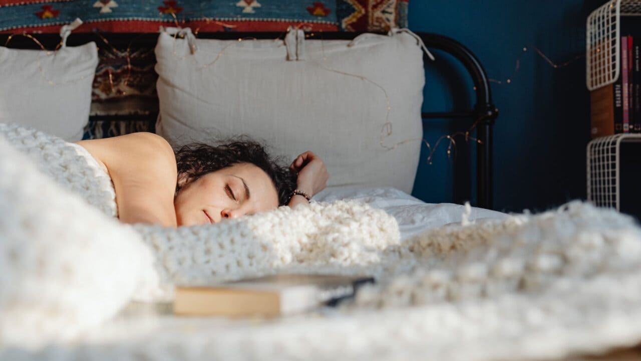 Woman sleeping on her side on a pillow in a sunlit bedroom