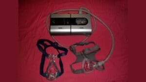 ResMed S9 CPAP machine with tubing and two mask styles on a red cloth