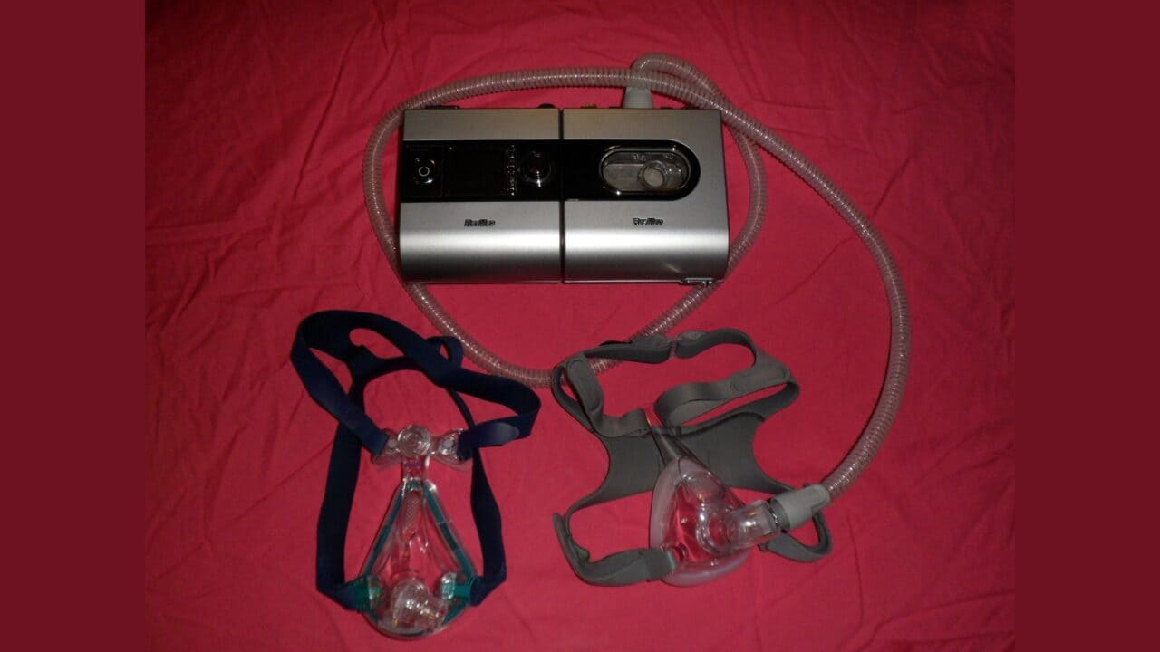ResMed S9 CPAP machine with tubing and two mask styles on a red cloth