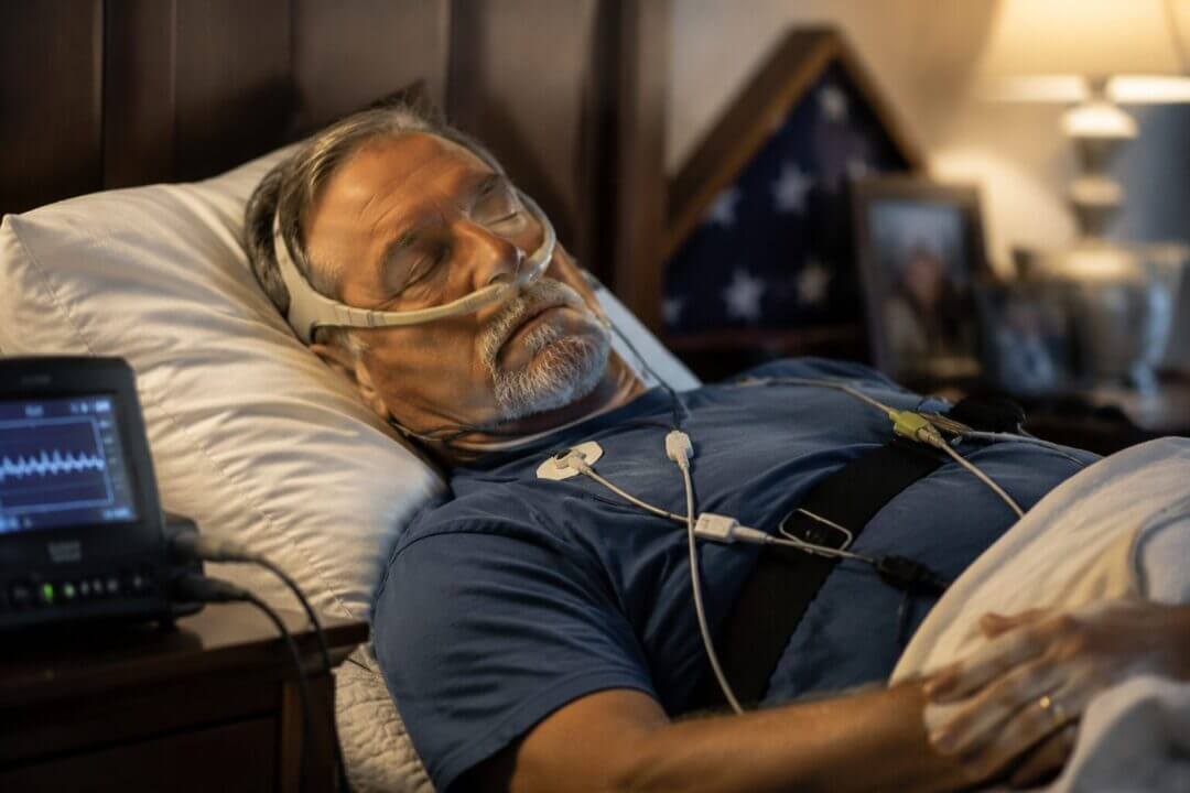 A veteran sleeping peacefully with subtle American flag elements and medical sleep monitoring equipment in soft, respectful