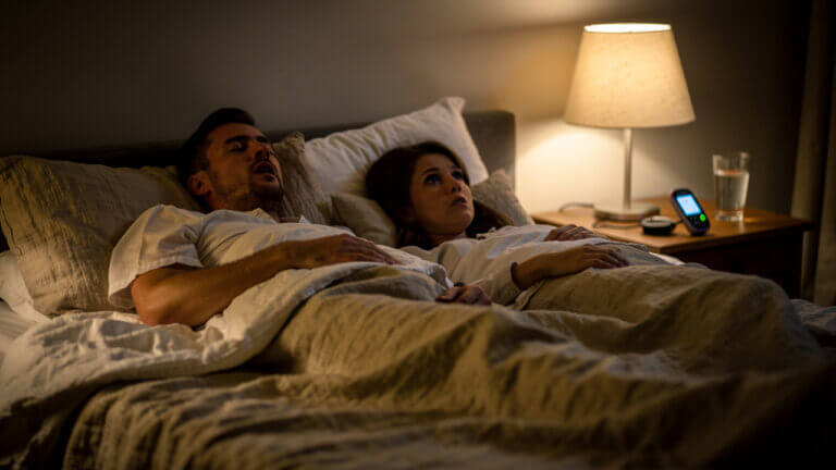 Couple in bed, man snoring, woman awake